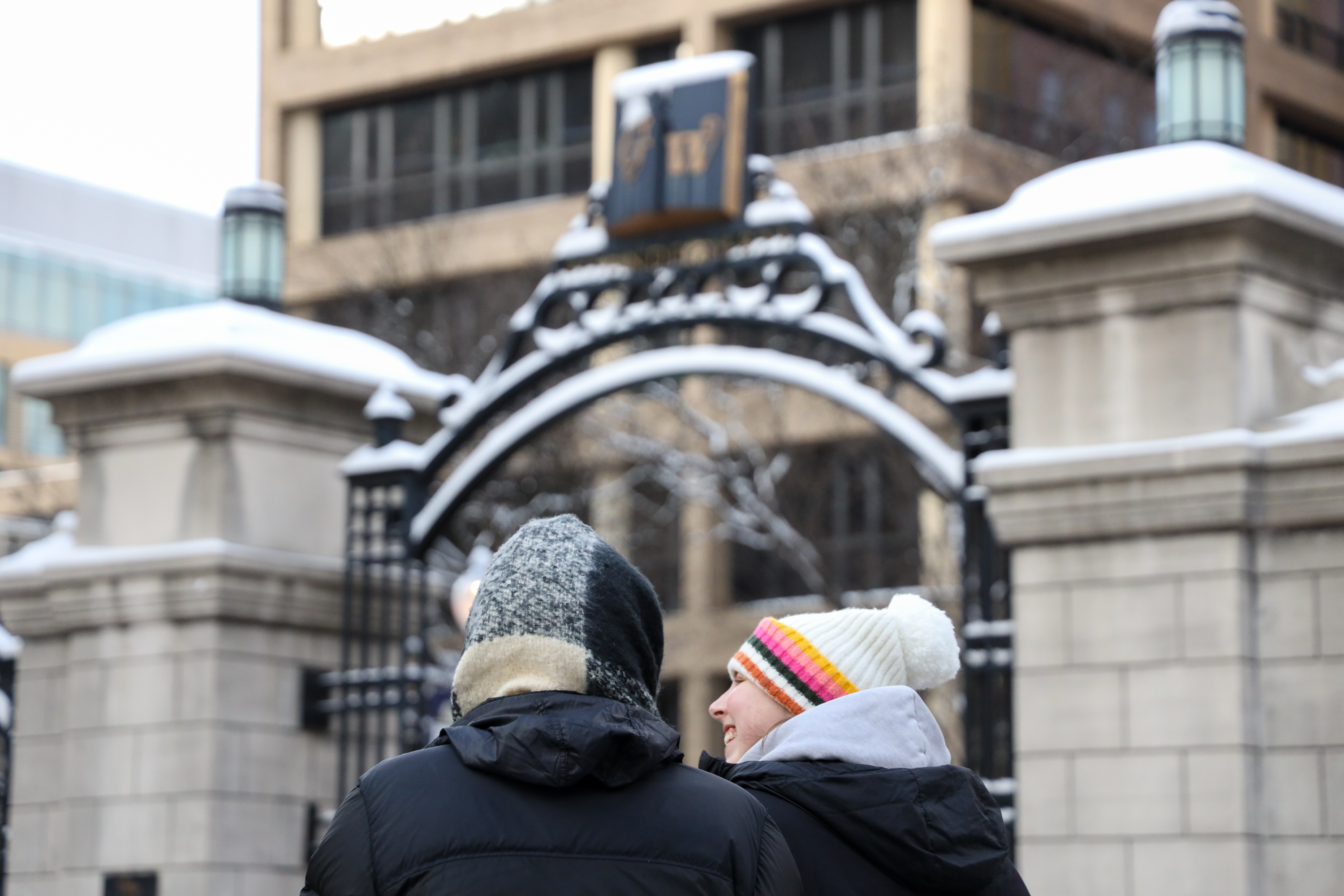 Two students talking in front of GW's gates on a snowy day. 