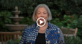 President Ellen M. Granberg standing outside. Play button on top of image. 